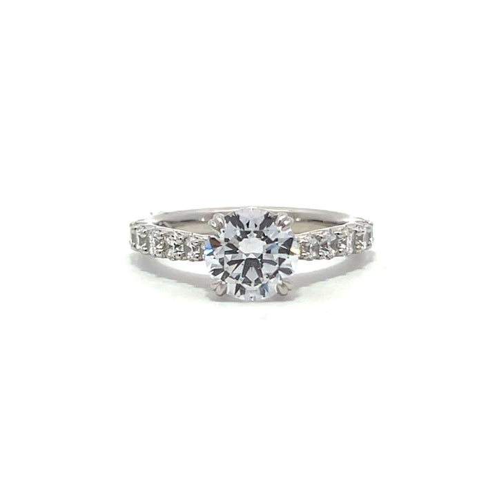 White gold round-shaped diamond engagement ring with a diamond band on a white background.