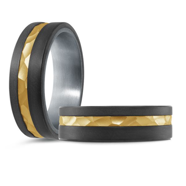 Black ceramic wedding band with a gold inlay and hammered texture on a white background.