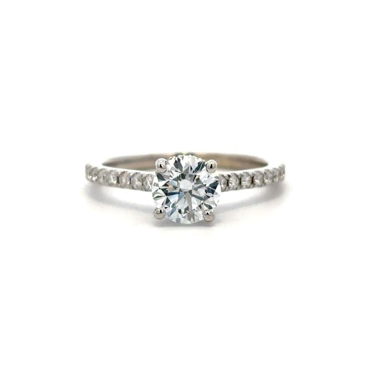 White gold diamond engagement ring with a halo setting and a diamond band on a white background.