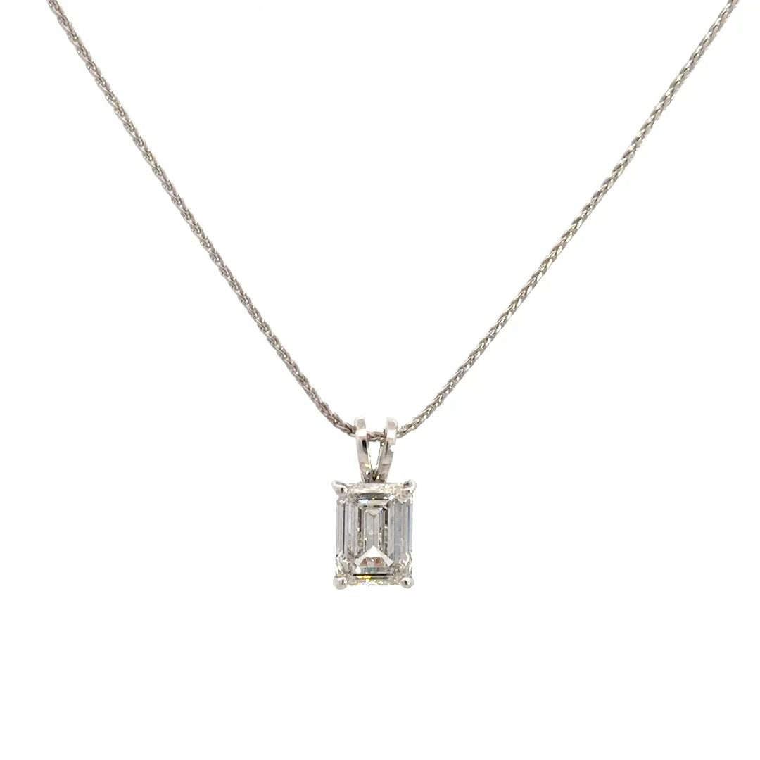 Front view of silver necklace with a emerald-cut diamond in a four-prong setting pendant on a white background.