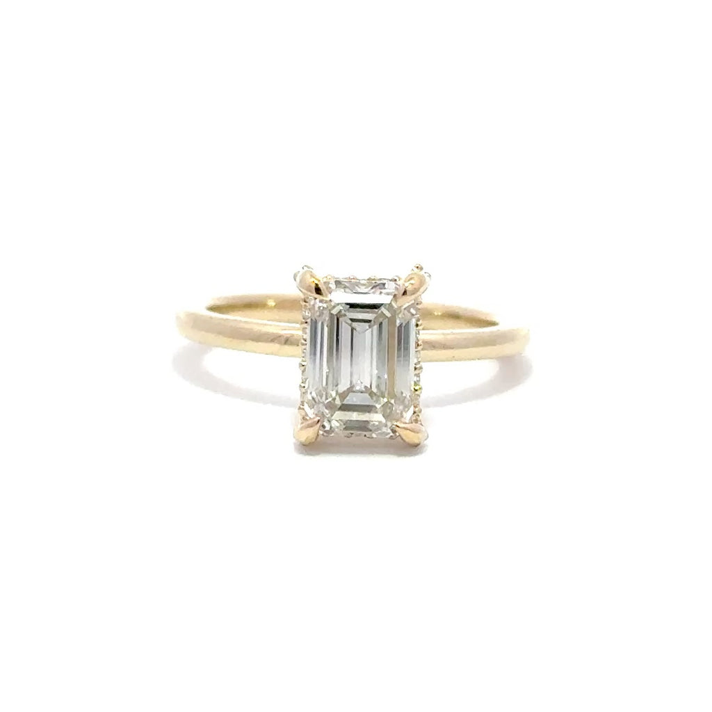 Yellow gold engagement ring with a center emerald cut diamond.