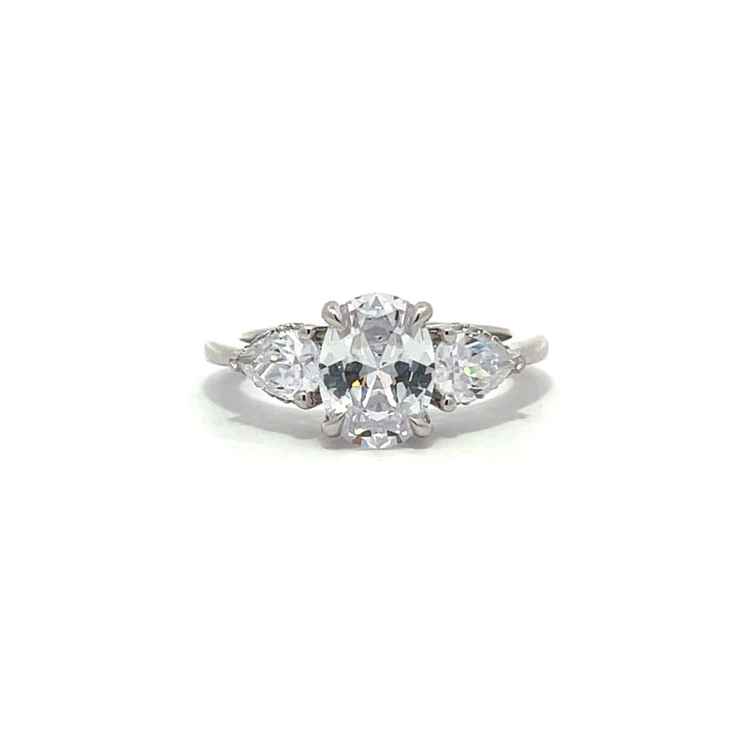 White gold three-stone diamond engagement ring with pear-shaped side stones on a white background.