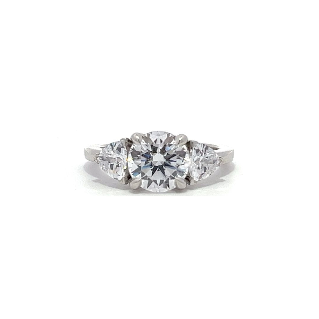 White gold three-stone diamond engagement ring with pear-shaped side stones on a white background