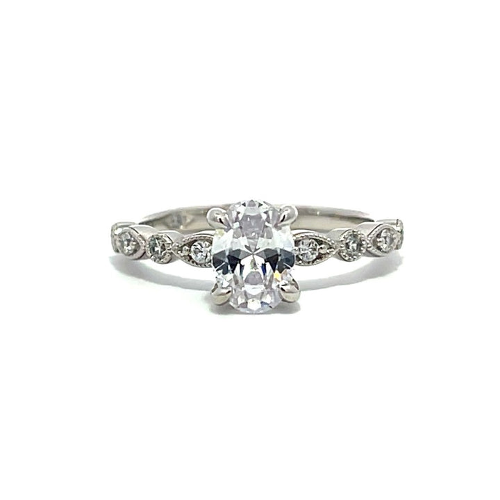 White gold oval diamond engagement ring with a diamond band on a white background.