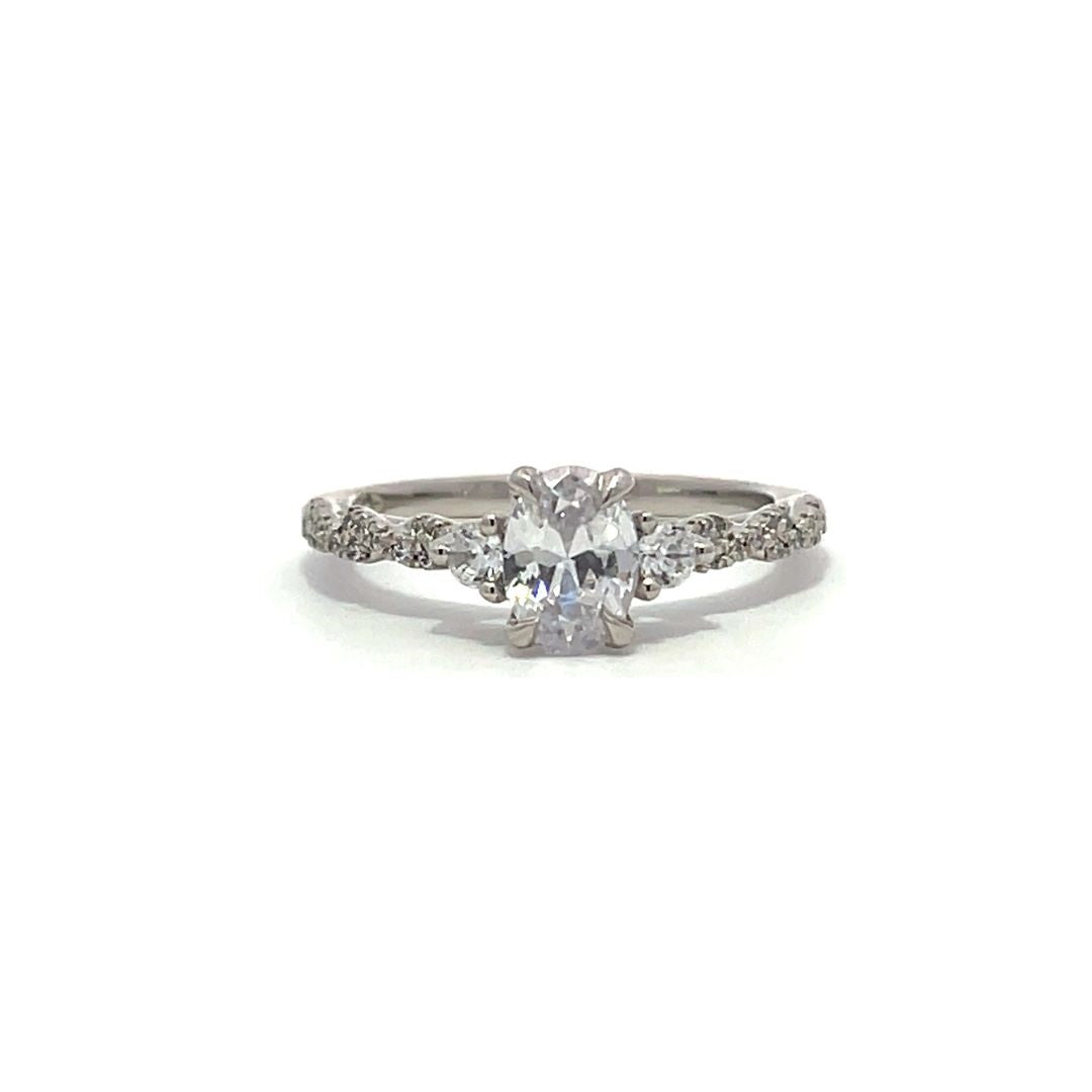 White gold oval diamond engagement ring with side stones and a diamond band on a white background.