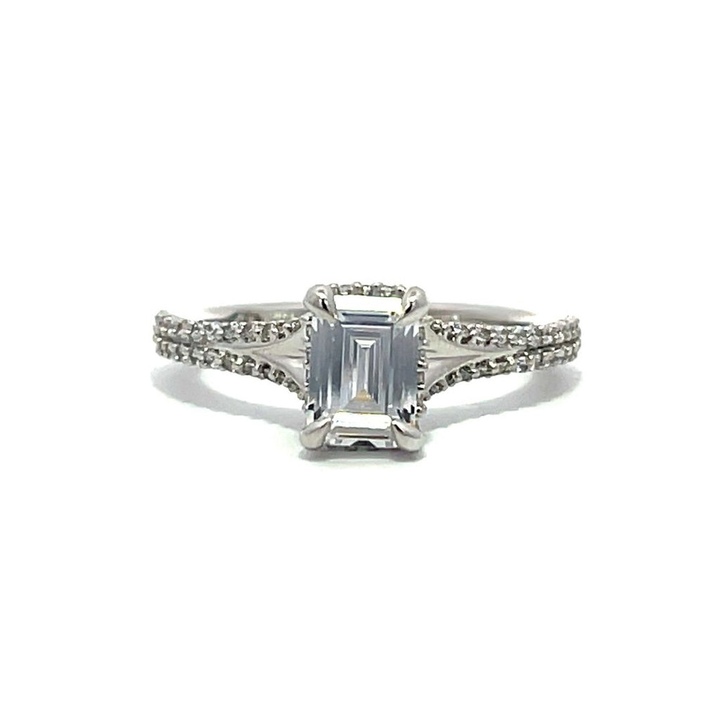 White gold emerald-cut diamond engagement ring with a diamond band on a white background.