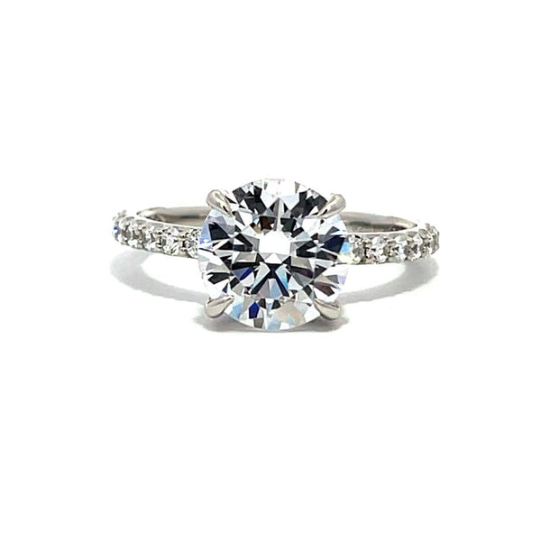 White gold round-shaped diamond engagement ring with a diamond band on a white background.