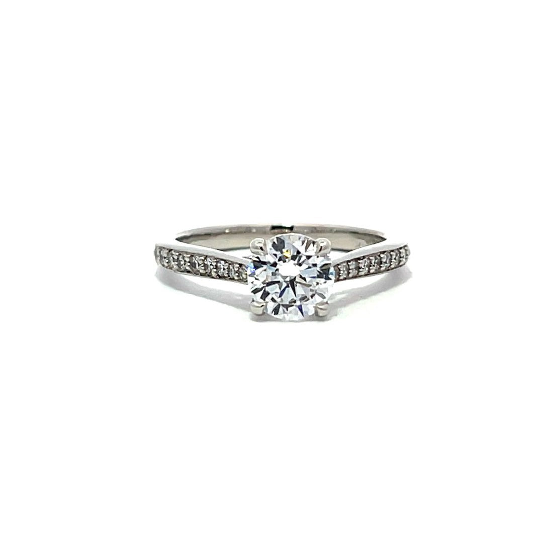 White gold round-shaped diamond engagement ring with a diamond band on a white background.