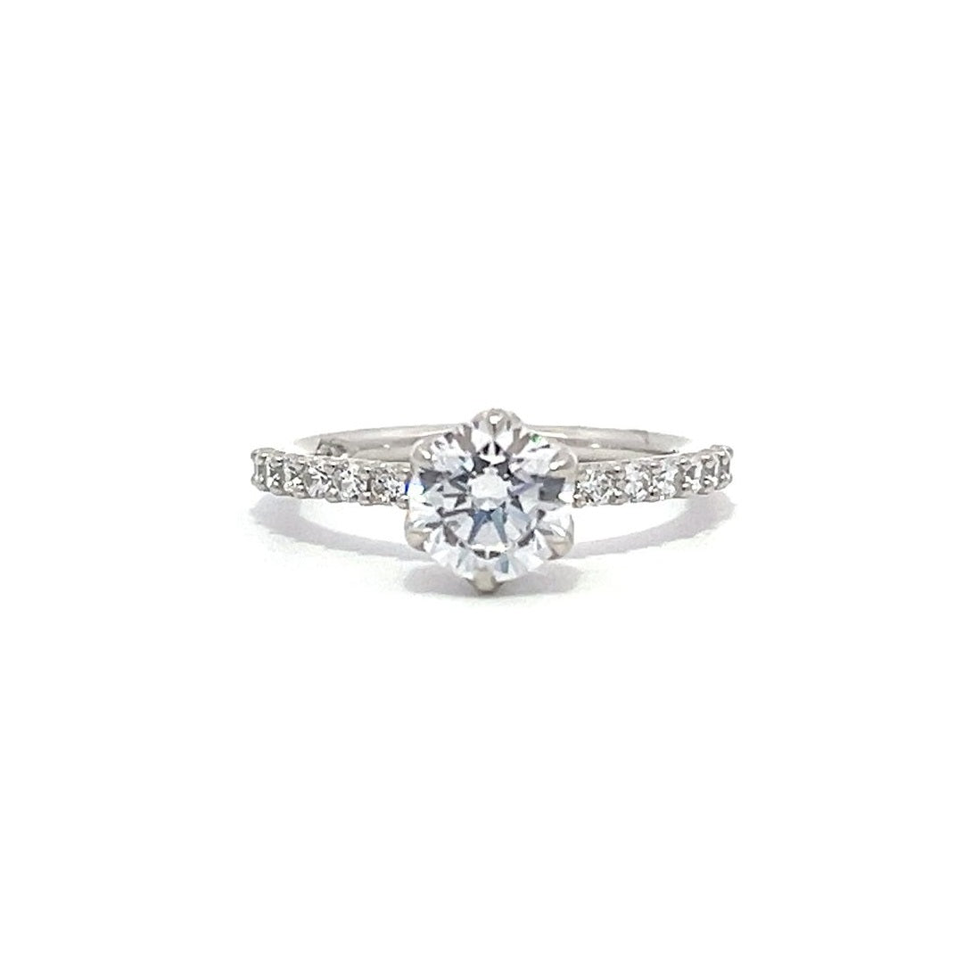 White gold round-shaped diamond engagement ring with a diamond band on a white background.