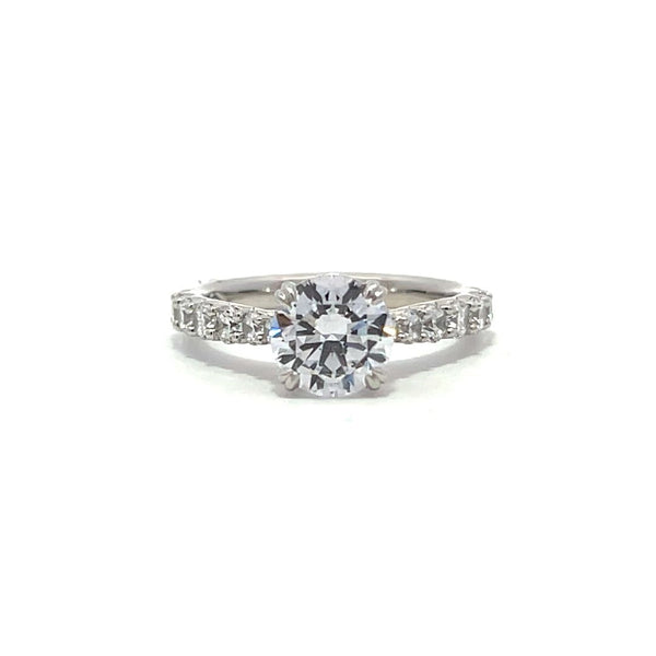 White gold round-shaped diamond engagement ring with a diamond band on a white background.