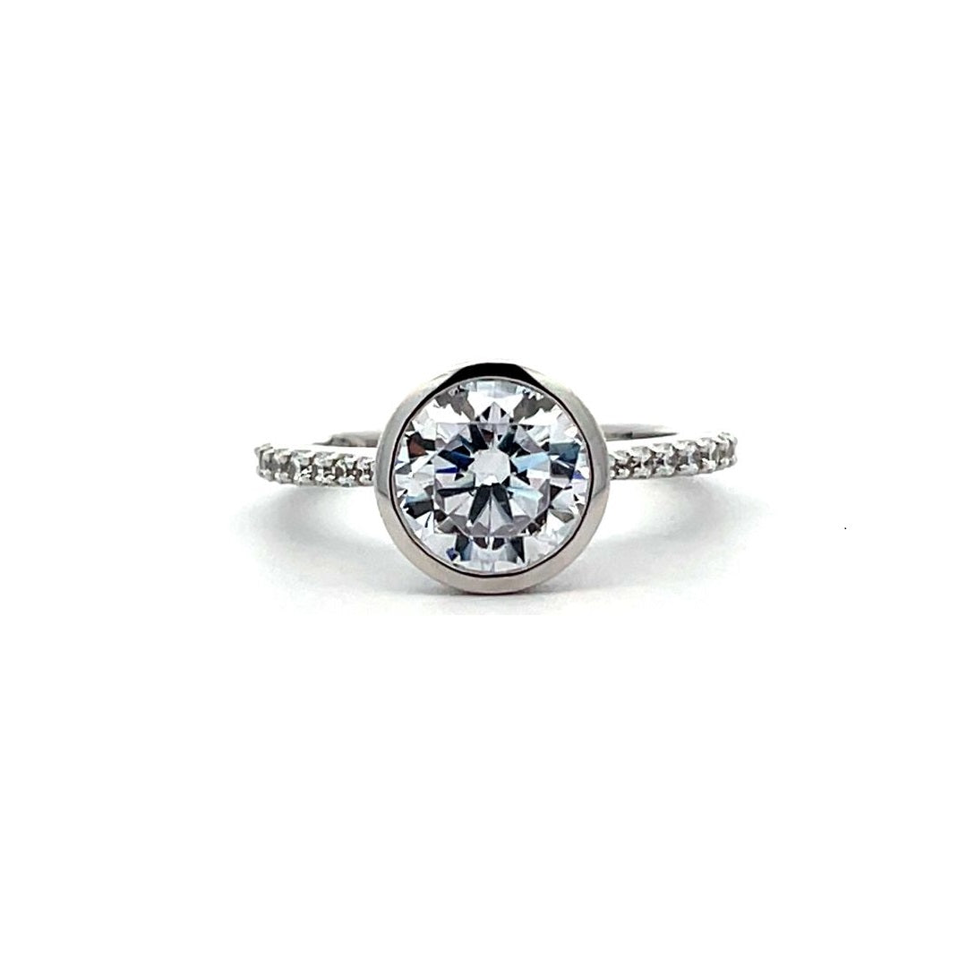 White gold bezel-set diamond engagement ring with a diamond band on a white background.