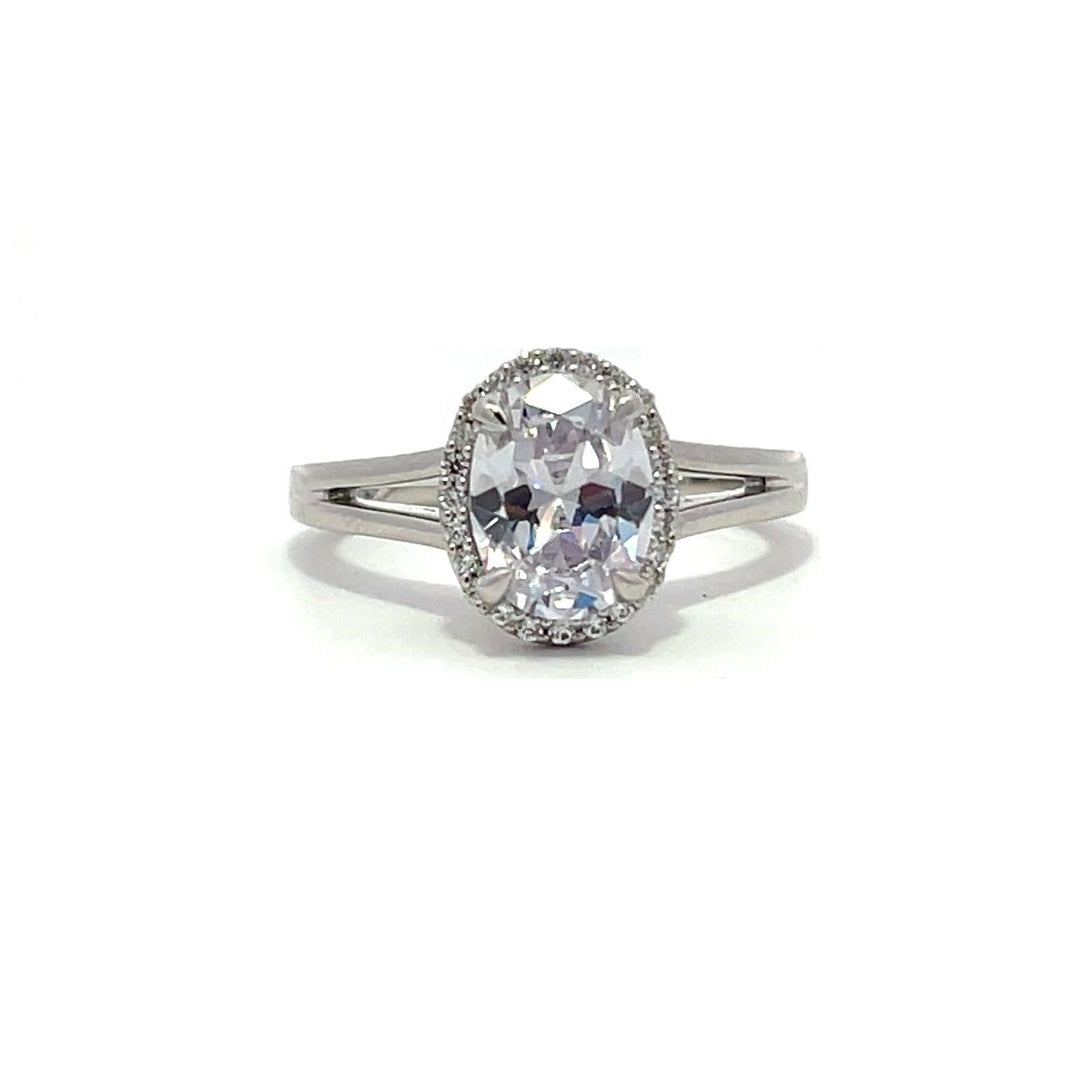 White gold oval diamond engagement ring with a halo setting and split shank on a white background