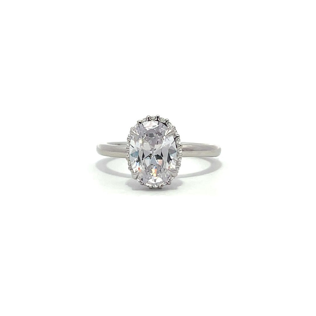 White gold oval diamond engagement ring with a halo setting on a white background