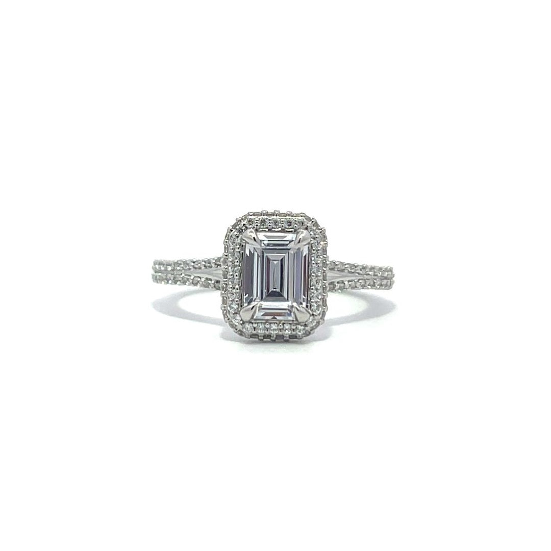 Silver emerald-cut engagement ring with a double halo setting on a white background