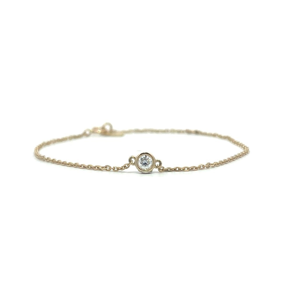 Yellow gold bracelet with a single diamond pendant in a bezel set on a white background.