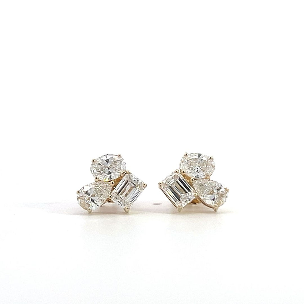 Yellow gold stud earrings with multiple diamond clusters featuring round, pear, and emerald-cut stones, on a white background.