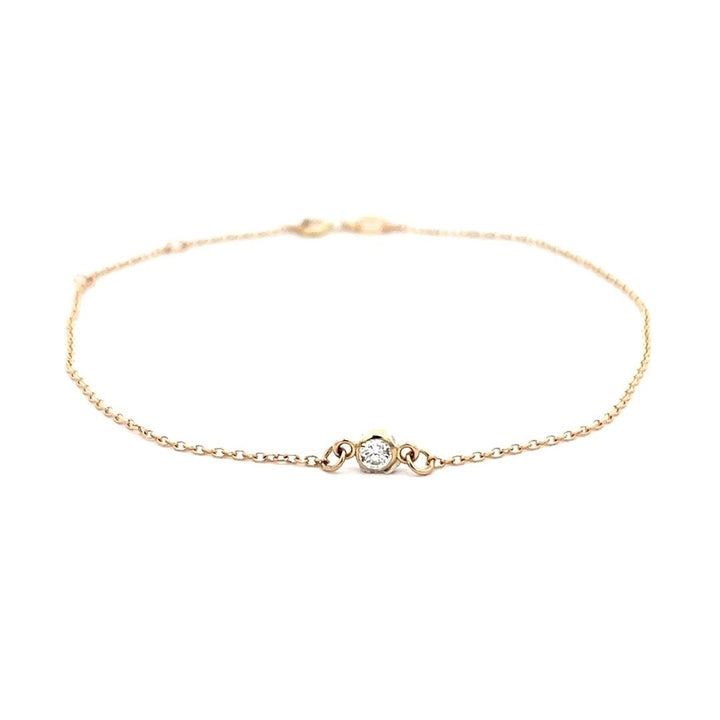 Yellow gold bracelet with a single diamond on a white background.