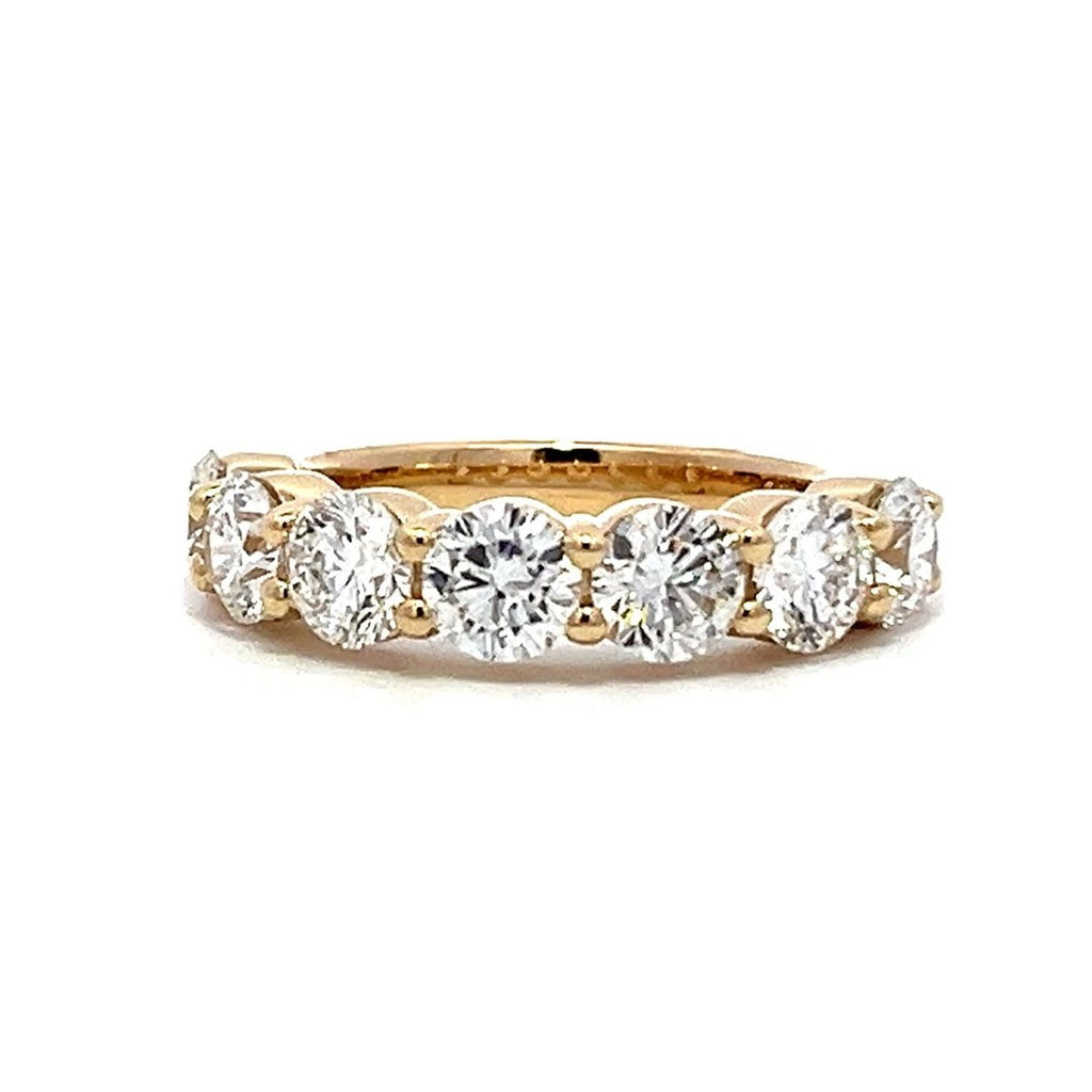 Yellow gold eternity band with round diamonds on a white background.