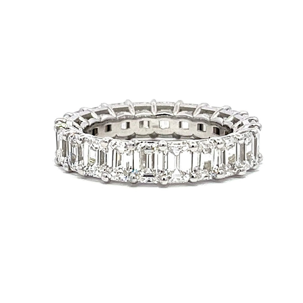 Silver eternity band with emerald-shaped diamonds on a white background.