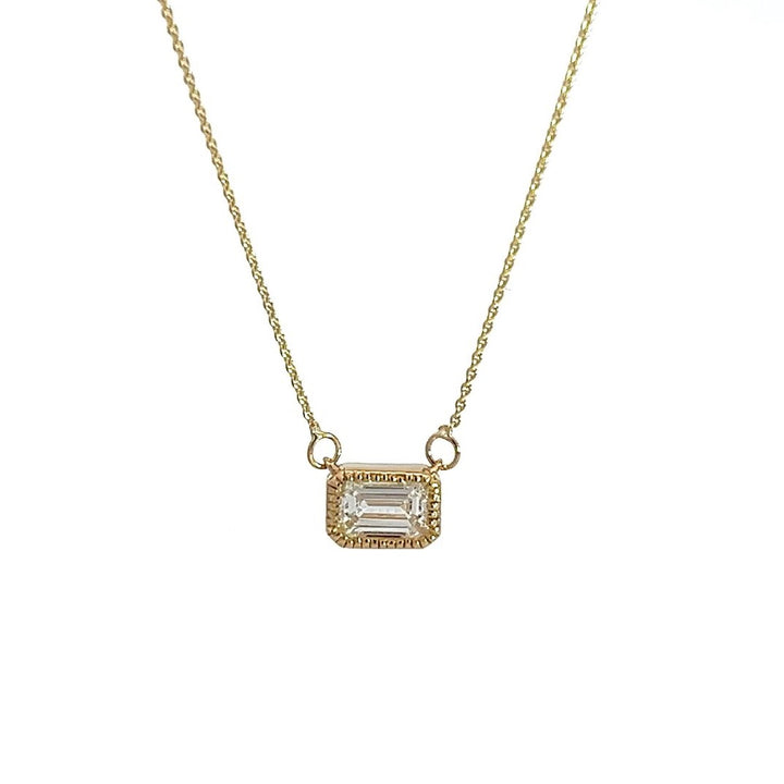 Yellow gold necklace with an emerald-cut diamond pendant on a white background.