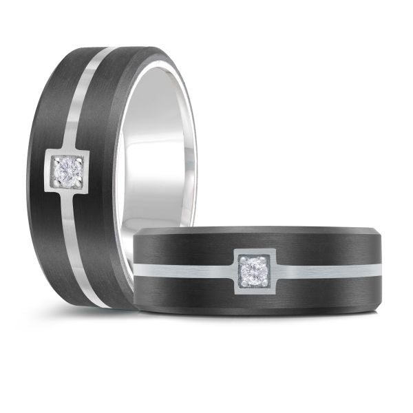 Black ceramic wedding band with a silver inlay and a single diamond on a white background