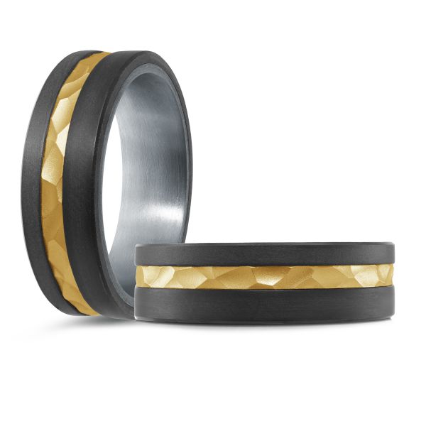 Black ceramic wedding band with a gold inlay and hammered texture on a white background.