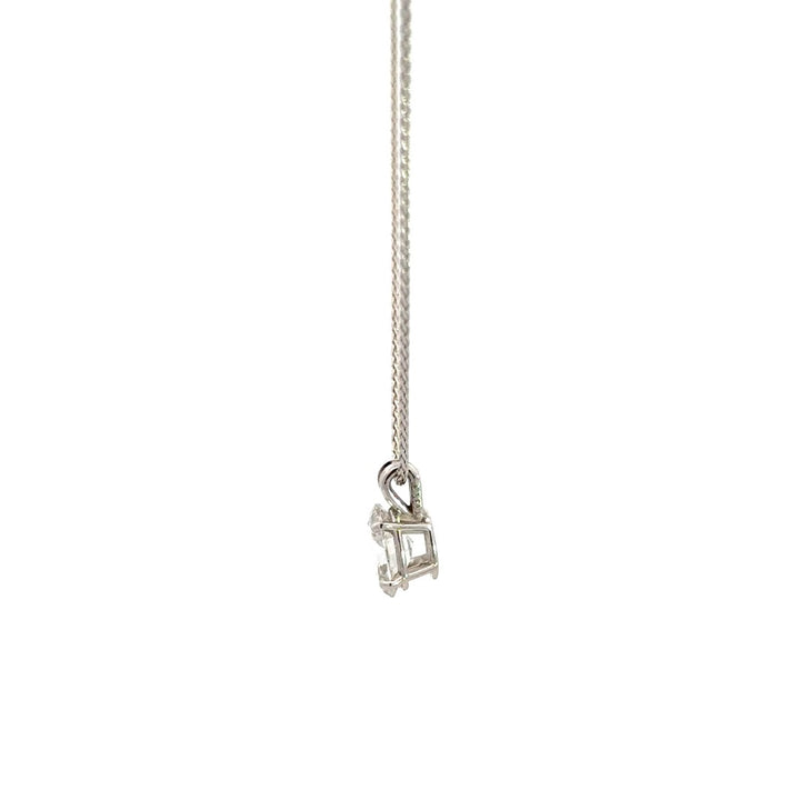 Side view of silver necklace with a oval-cut diamond in a four-prong setting pendant on a white background.