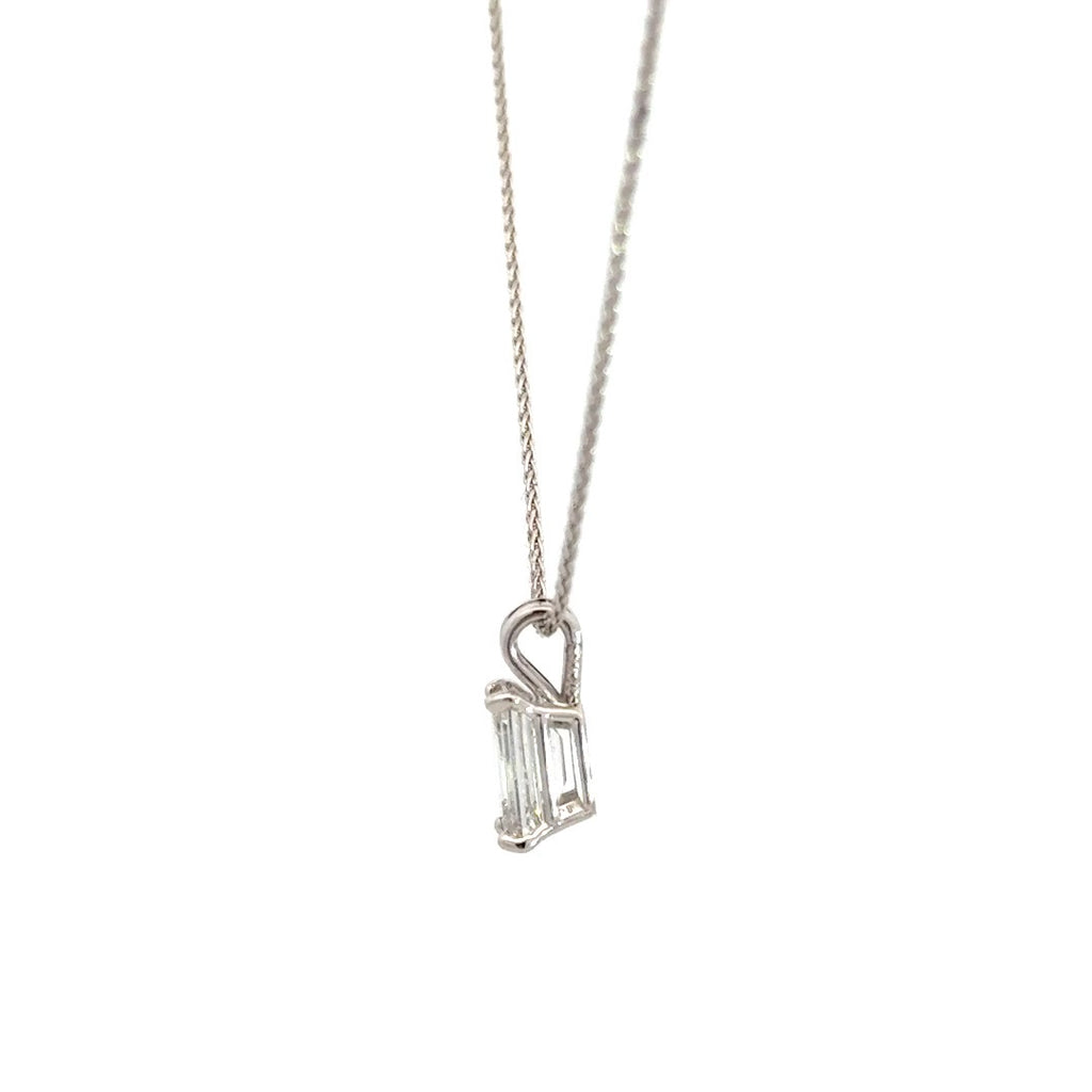 Side view of silver necklace with a emerald-cut diamond in a four-prong setting pendant on a white background.