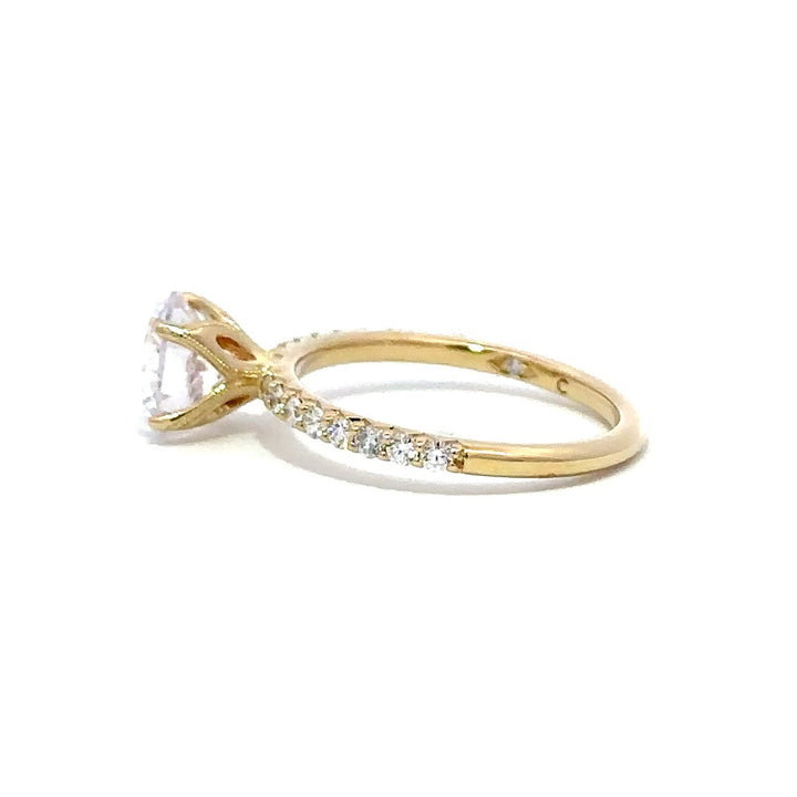 Side view of a gold engagement ring with a round-cut center diamond.