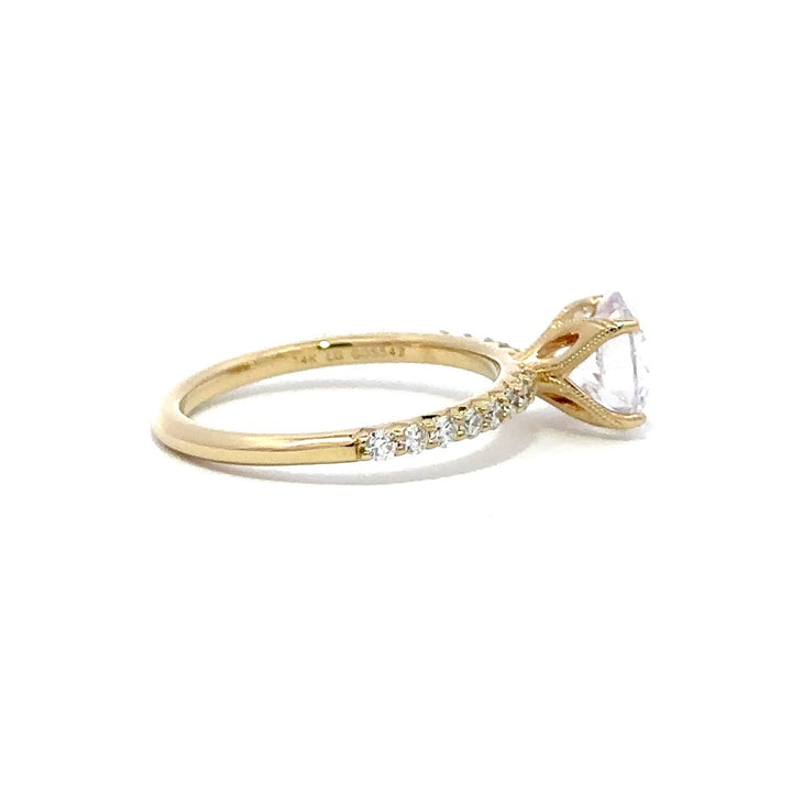 Side view of a gold engagement ring with a round-cut center diamond.