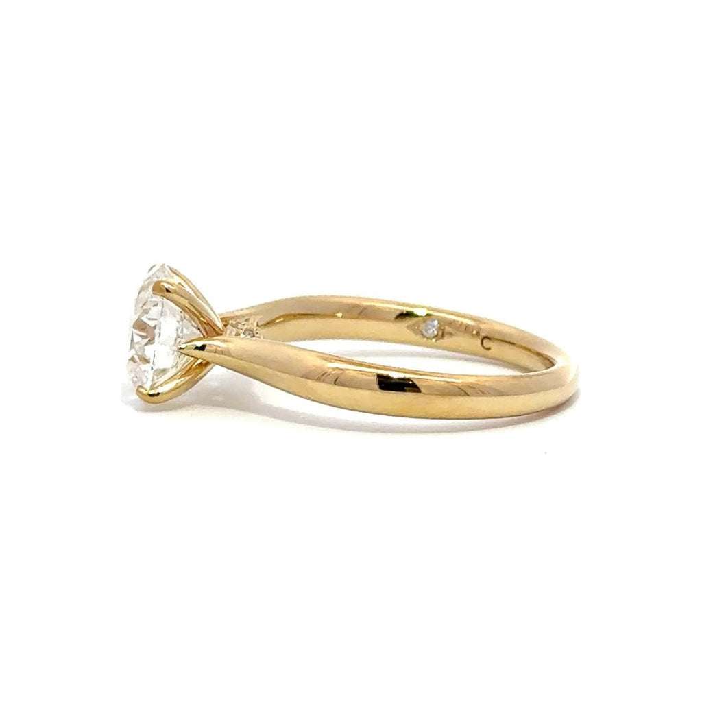 Side view of gold engagement ring with a round-cut center diamond.