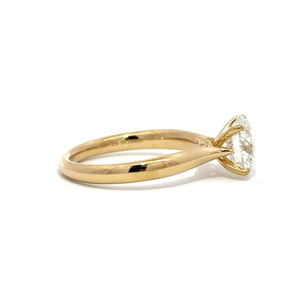 Side view of gold engagement ring with a round-cut center diamond.