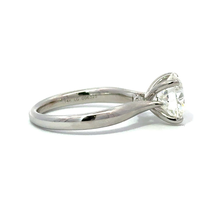 Side view of silver engagement ring with a round-cut center diamond.