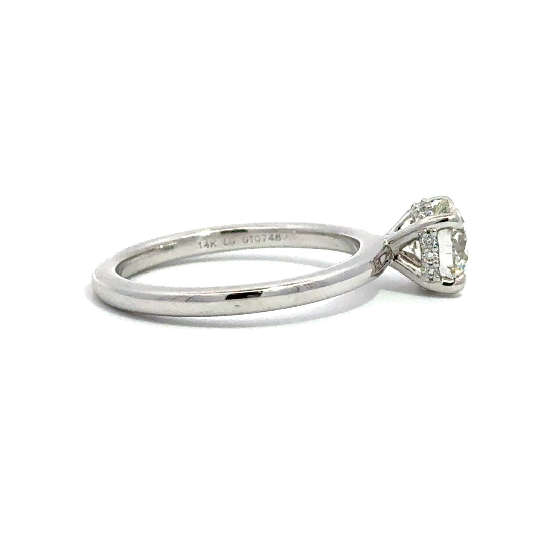 Side view of silver engagement ring with a round-cut center diamond.