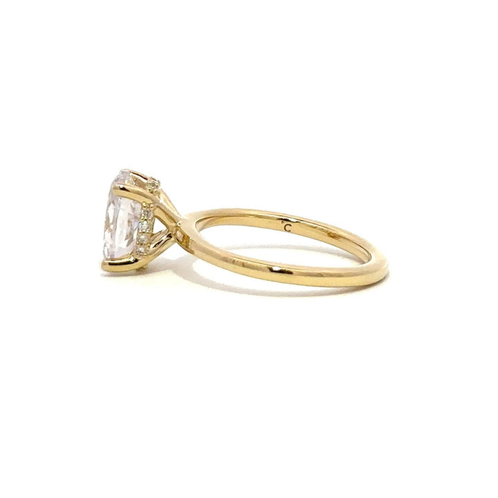 Side view of gold engagement ring with a oval-cut center diamond.