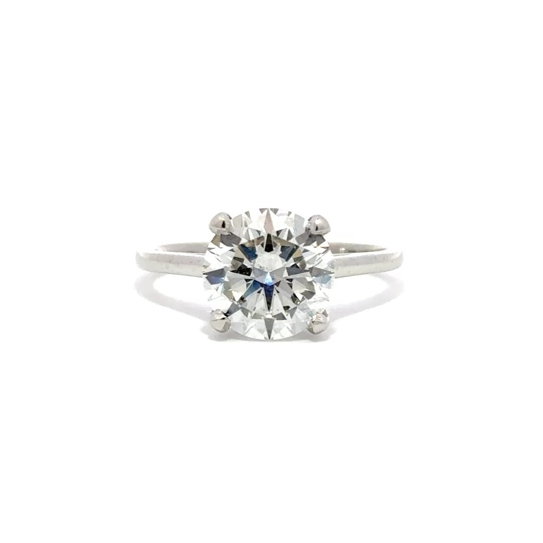 Silver solitaire engagement ring with a round-cut diamond center stone on a white background.