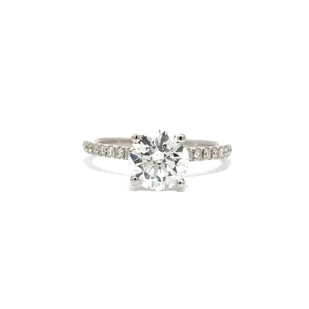 Silver gold solitaire engagement ring with a round cut diamond center stone on a white background.