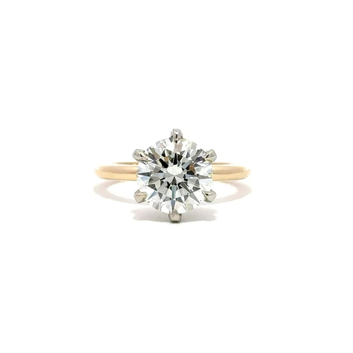 Yellow gold solitaire engagement ring with a round-cut diamond center stone and silver prong on a white background.