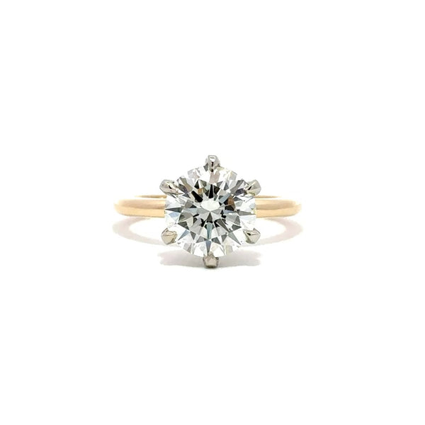 Yellow gold solitaire engagement ring with a round-cut diamond center stone and silver prong on a white background.