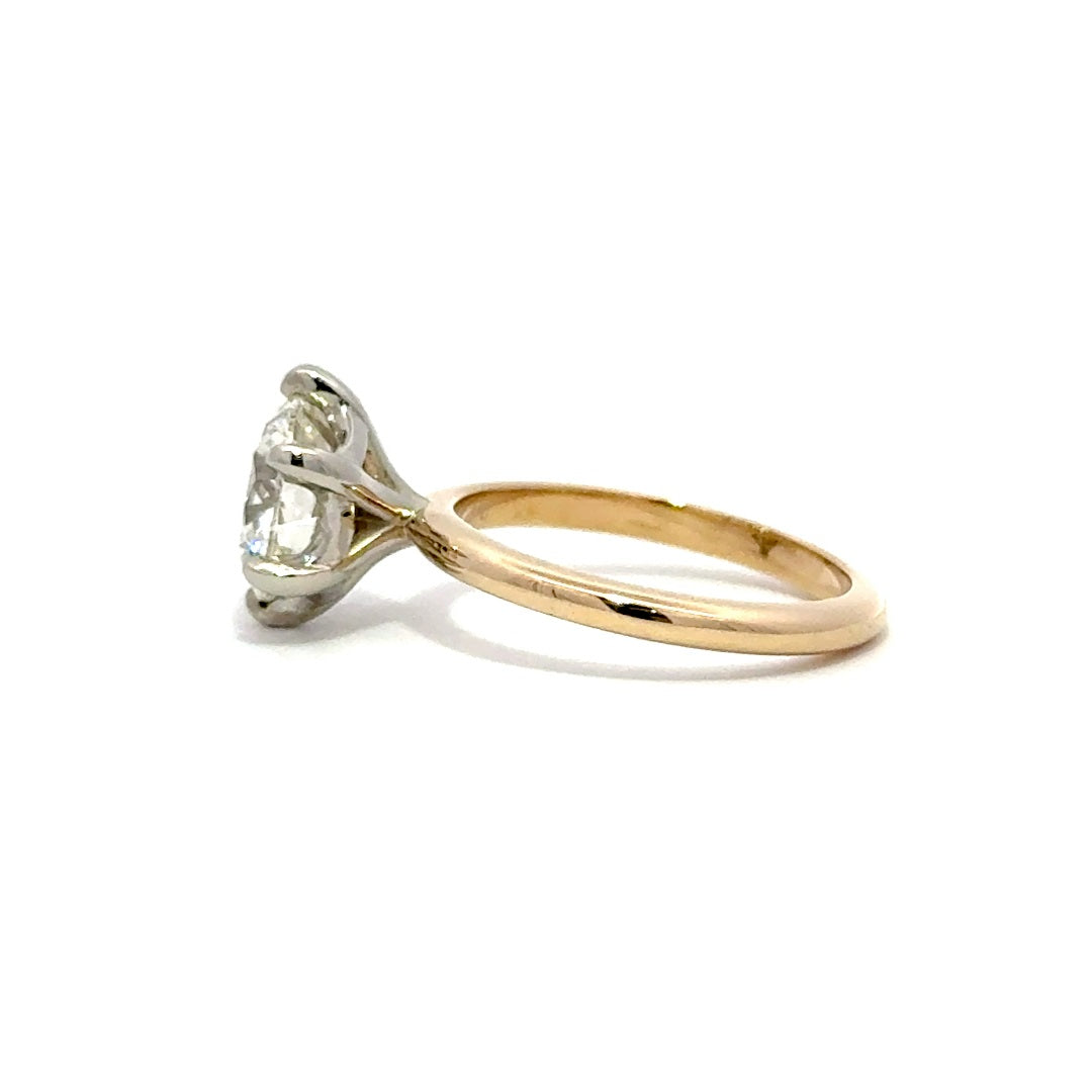 Yellow gold solitaire engagement ring with a round-cut diamond center stone and silver prong on a white background.