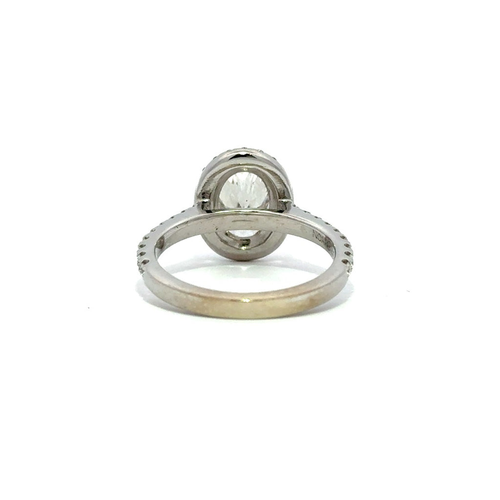 Silver ring with an oval-cut diamond center stone surrounded by a diamond halo and a diamond-studded band, on a white background.