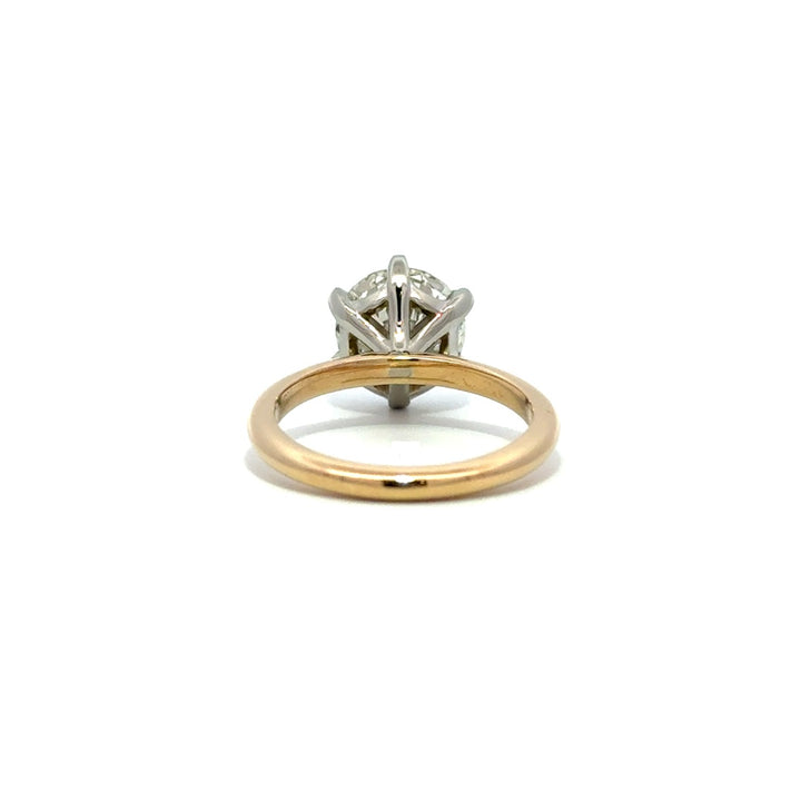 Yellow gold solitaire engagement ring with a round-cut diamond center stone and silver prong on a white background.