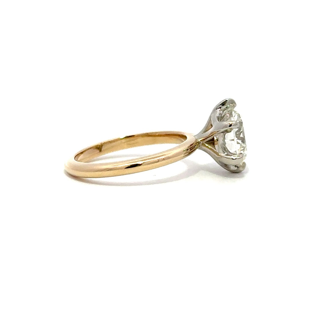 Yellow gold solitaire engagement ring with a round-cut diamond center stone and silver prong on a white background.