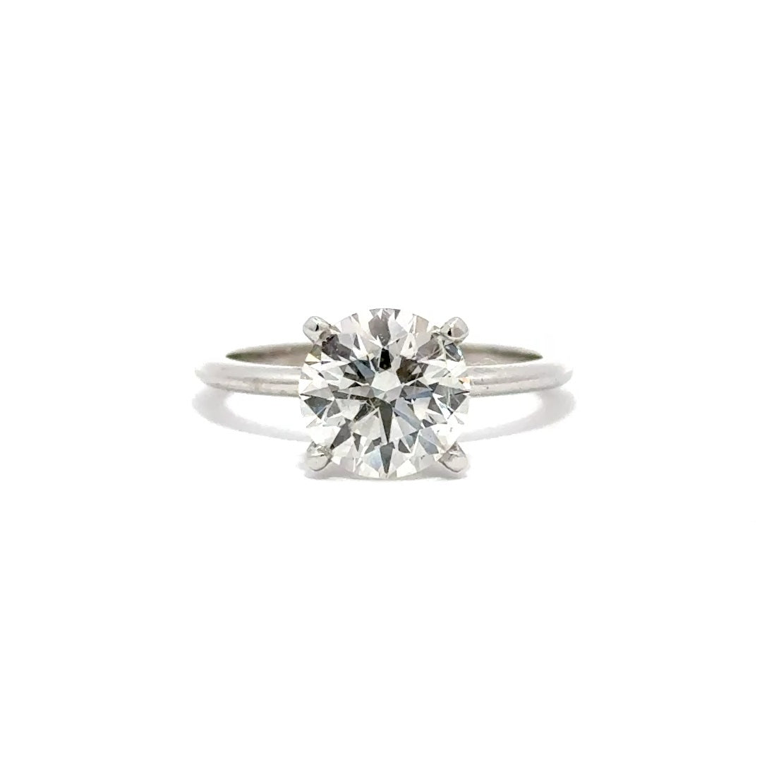 Silver solitaire engagement ring with a round-cut diamond center stone on a white background.