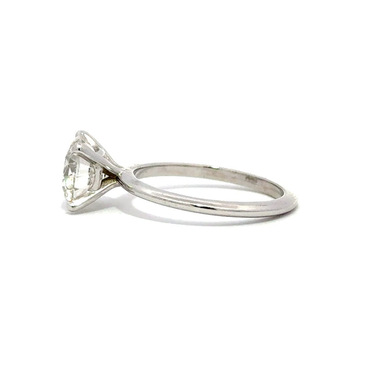 Silver solitaire engagement ring with a round-cut diamond center stone on a white background.