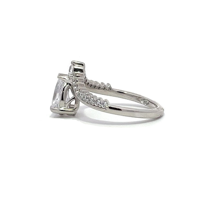 White gold pear-shaped diamond engagement ring with a diamond band on a white background