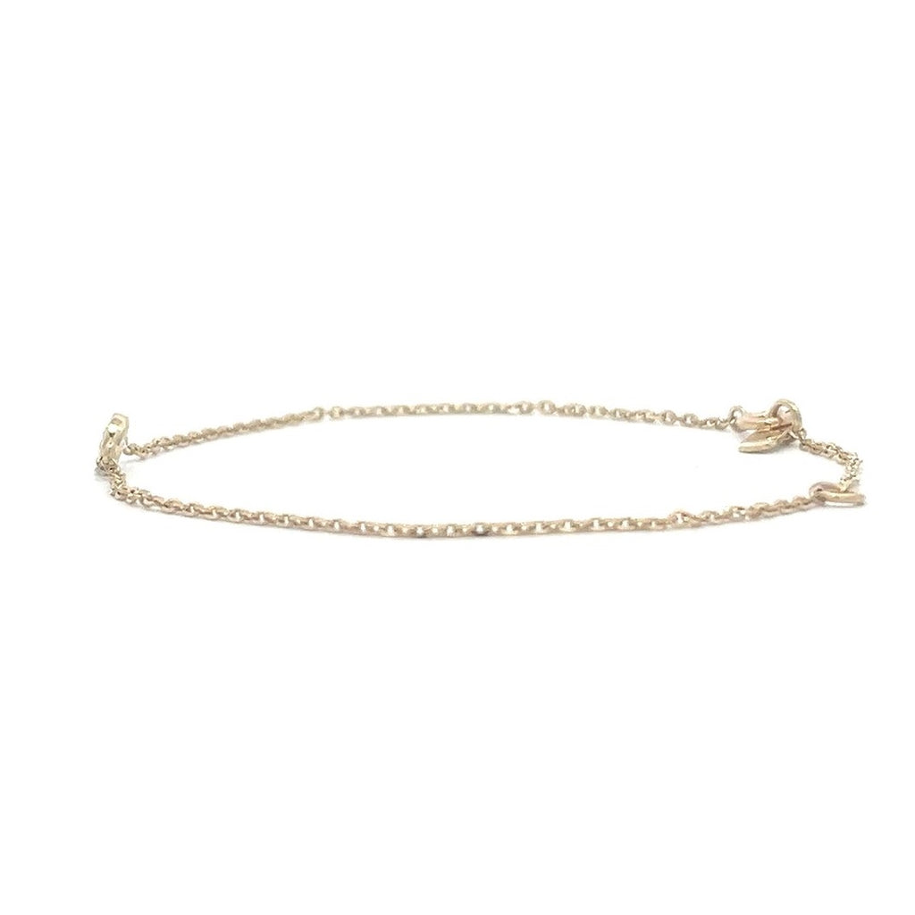 Yellow gold bracelet with a single diamond pendant in a bezel set on a white background.