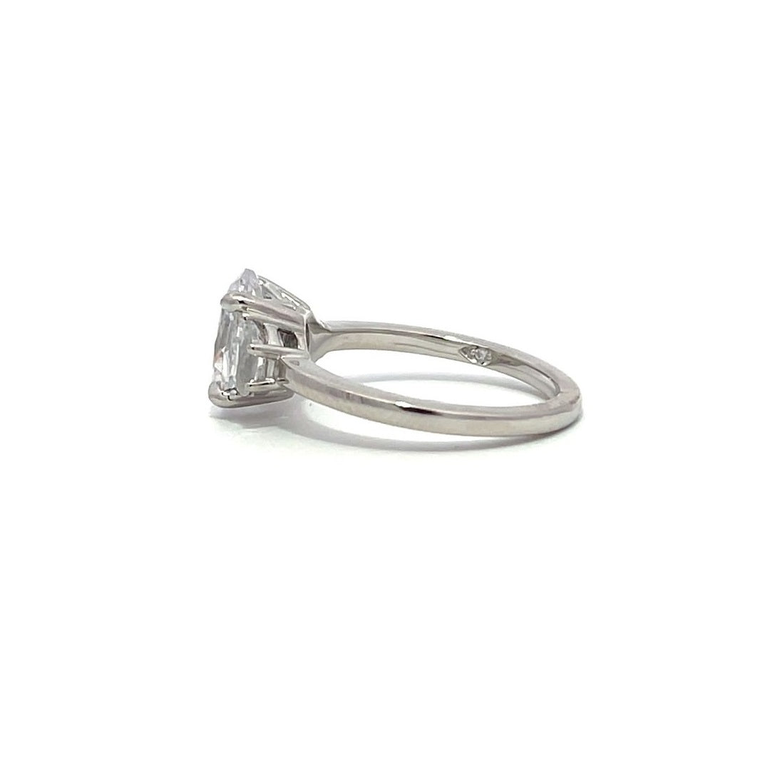 White gold three-stone diamond engagement ring with pear-shaped side stones on a white background.