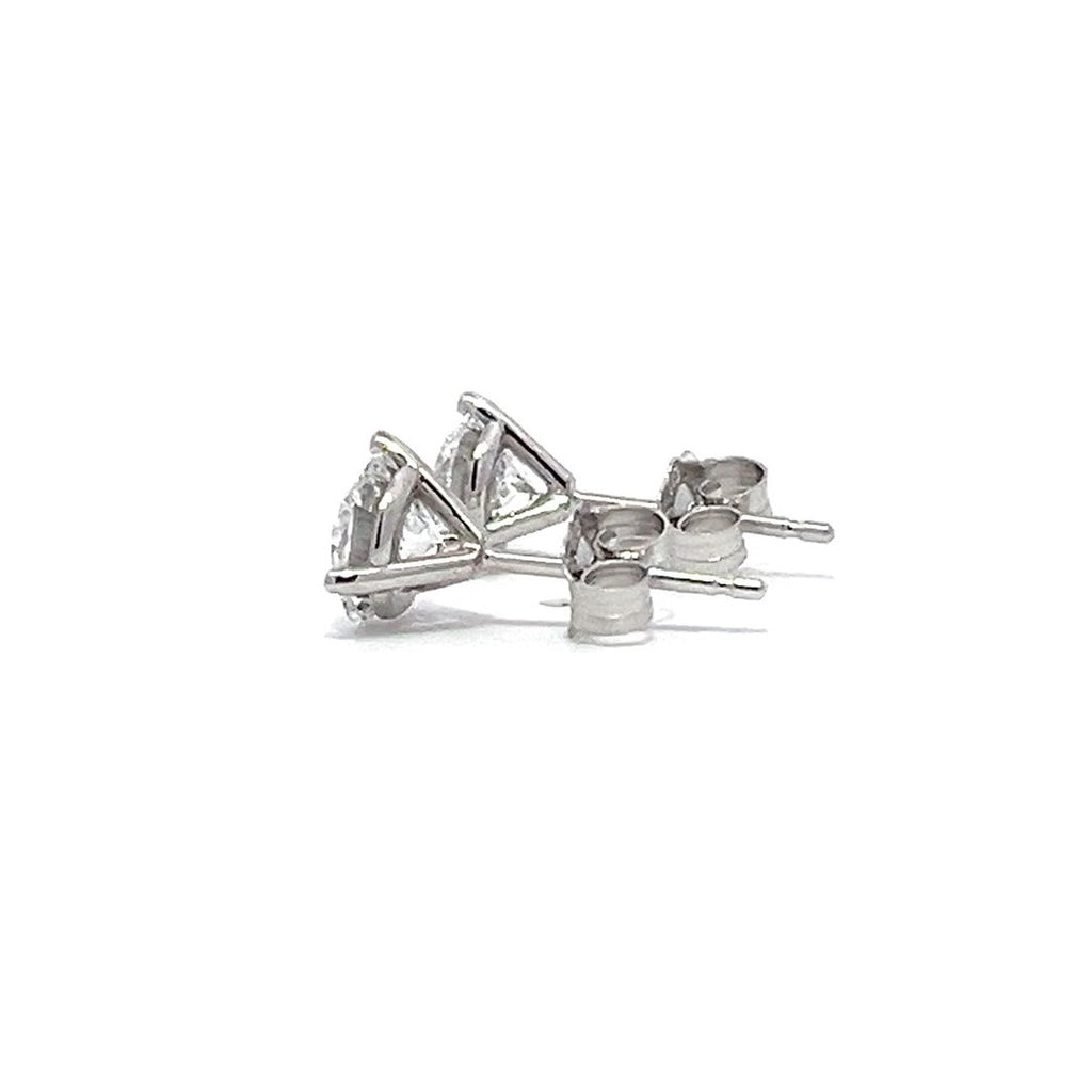 Pair of white gold stud earrings with a triangular setting of diamonds on a white background.