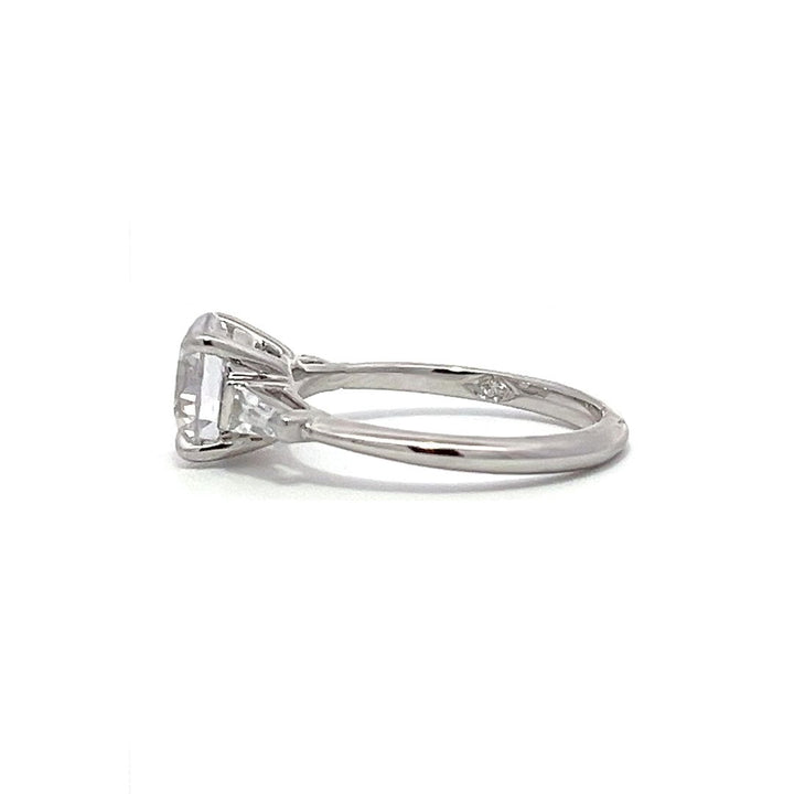  White gold three-stone diamond engagement ring with round-cut center stone and baguette side stones on a white background.